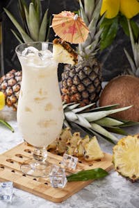 Delicious pina colada cocktail with tropical fruits and umbrella garnish.