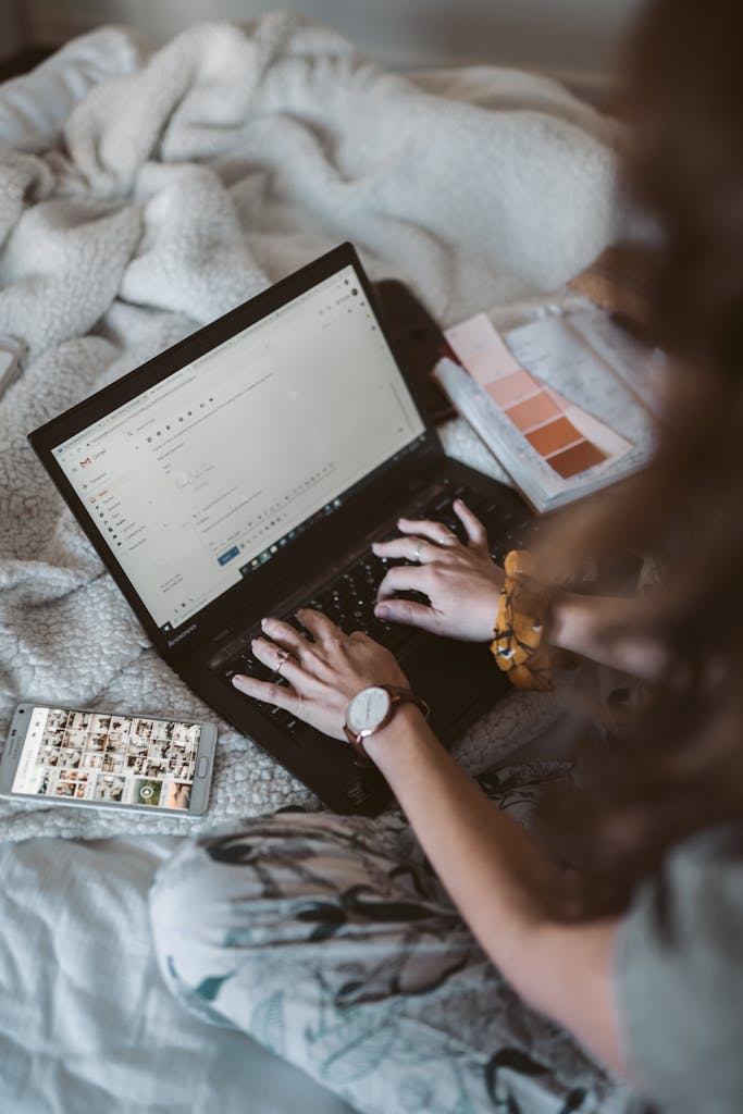 Adult woman typing on a laptop in a cozy home setting, emphasizing remote work and comfort.